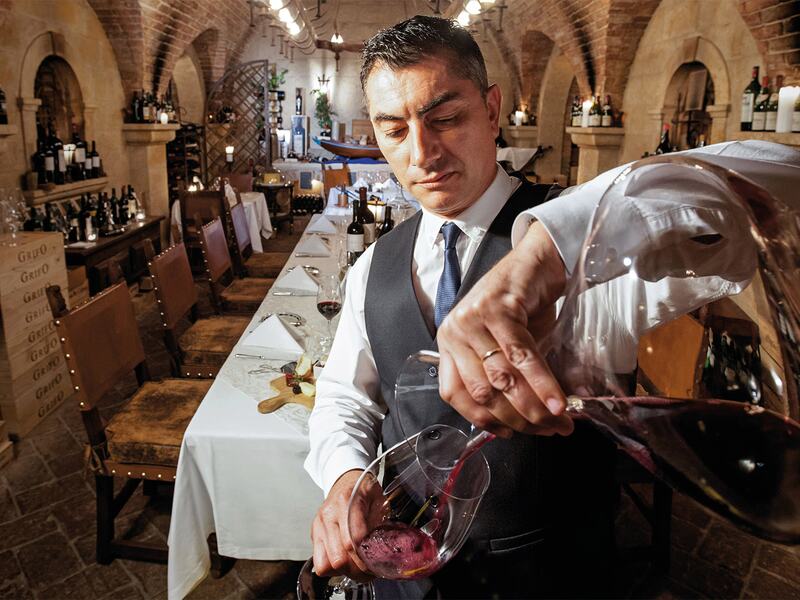 Cave de vinhos: Sommlier serving wine.