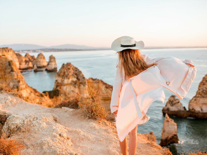 Beyond the resort: Woman walking on Algarve Beach.